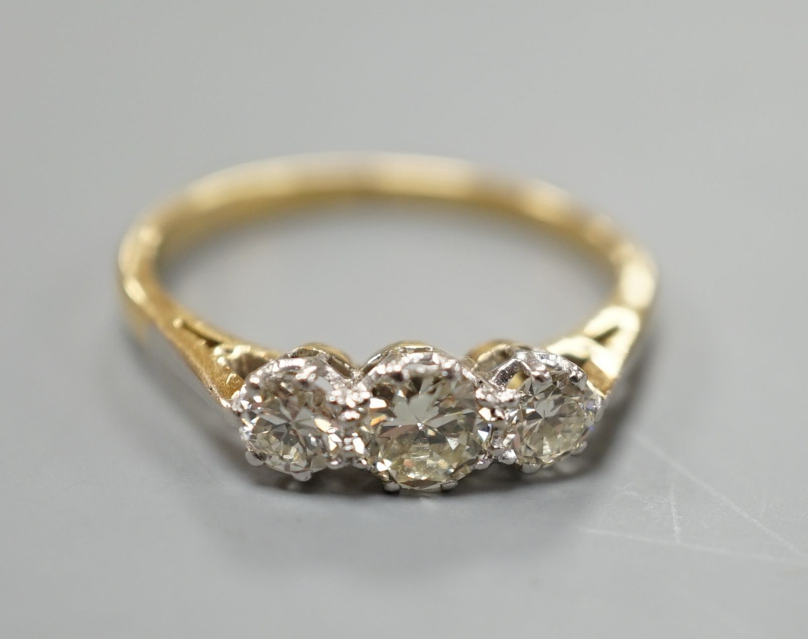 An 18ct gold and platinum three stone diamond ring, size M, gross 2.4 grams.